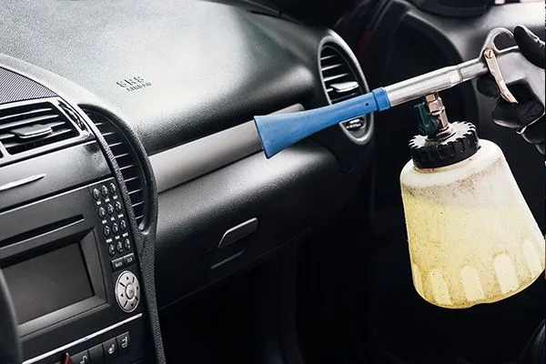 Cleaning tool spraying a car's dashboard during an interior detail