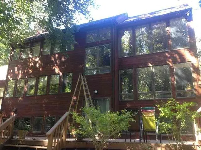 Wood-sided home with large windows and a deck after exterior painting
