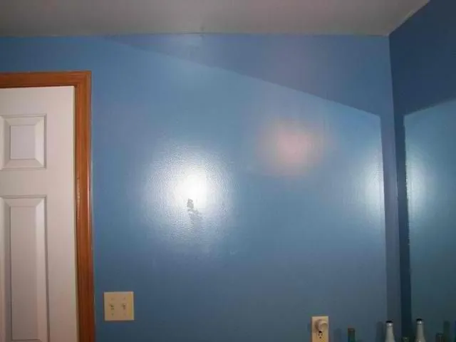 Bedroom with medium blue painted walls and natural wood door trim