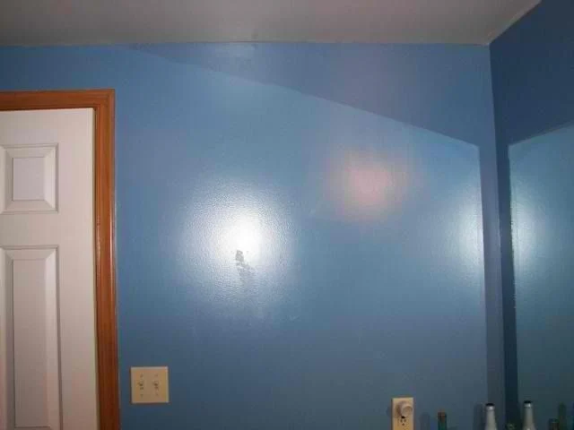 Bedroom with medium blue painted walls and natural wood door trim