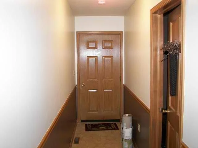 Hallway with white painted walls and wood trim leading to a front door
