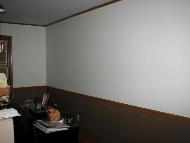 Room painted with white upper walls and dark gray lower walls below a wood chair rail
