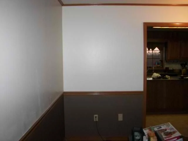 Two-tone white and gray painted wall with a wood chair rail beside a kitchen